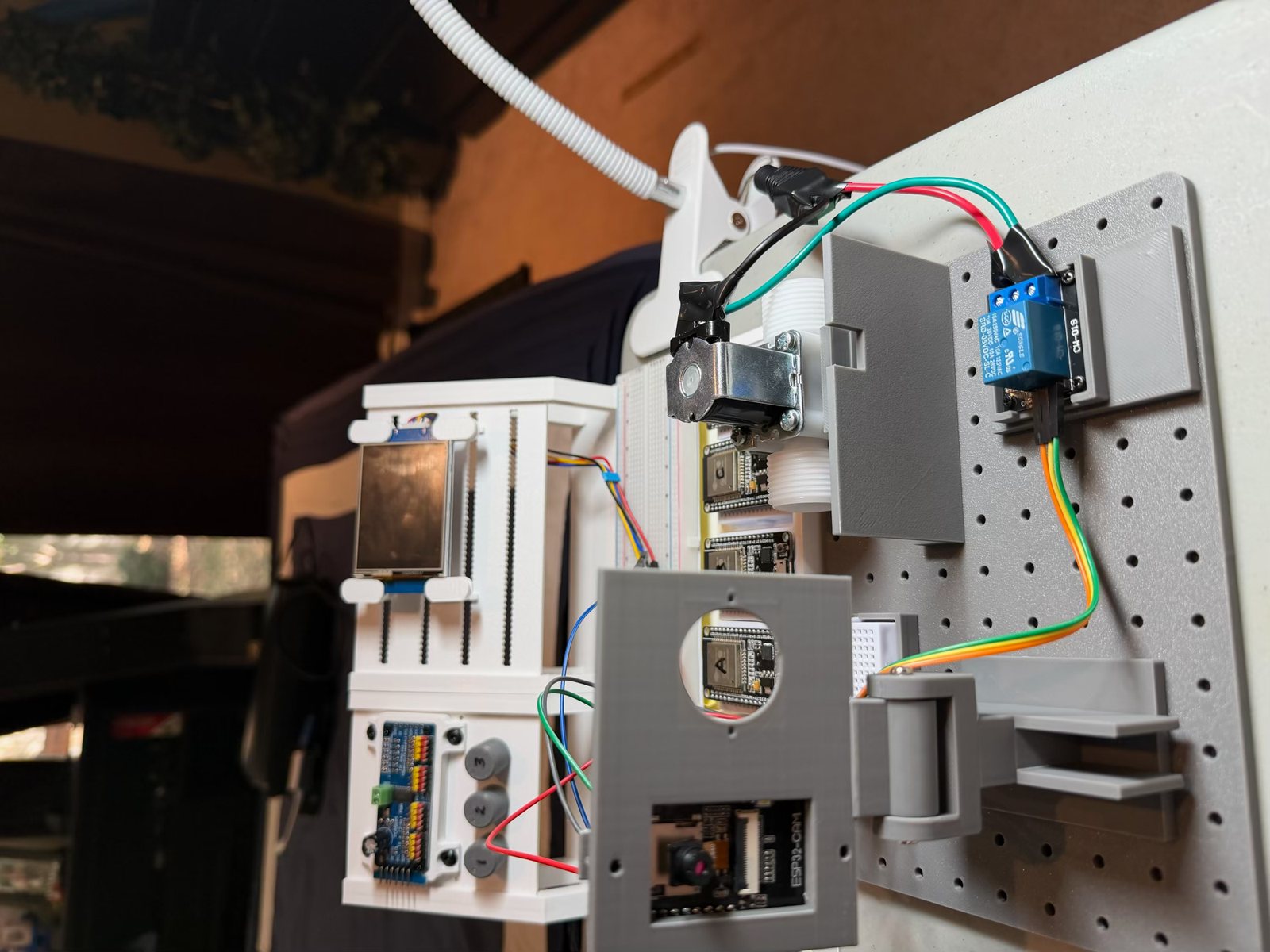 The printed v2 kit on the rig, standing upright: the camera head on its hinge in front, the valve and relay above, the rig's display and servo driver behind