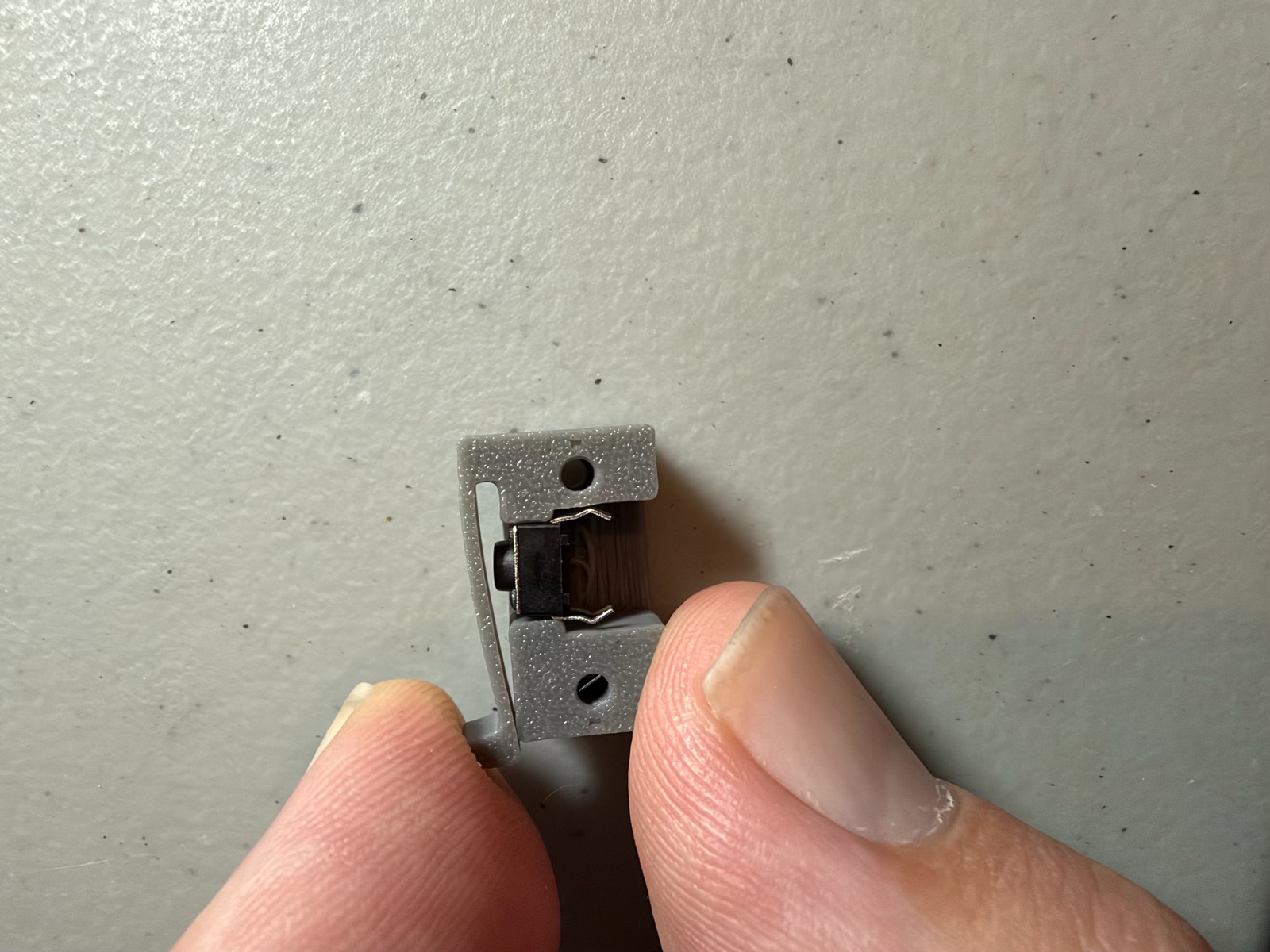 Pressing the holder's leaf with two fingers: the leaf bends but stays well short of the button